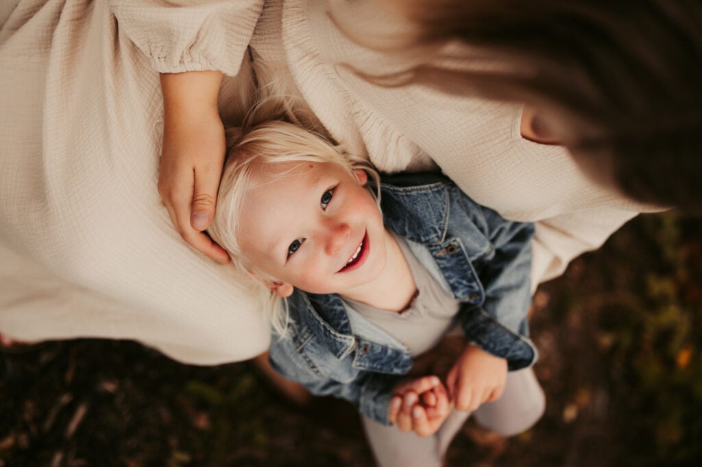 Family Photographer, child resting head in mother's lap and looking up at camera