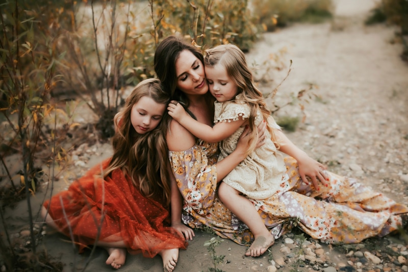 Family Photographer, mother sitting down on the ground with two daughters